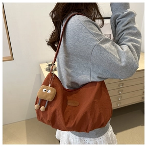 Detail of orange crescent bag with toast plush charm and fashion patch on shoulder