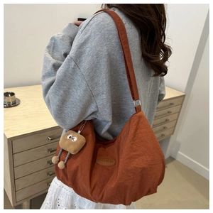 Detail of caramel nylon tote bag with fashion tag and cute plush toast keychain accessory