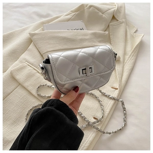 Détail du petit sac argenté matelassé avec fermoir rotatif sur une veste beige chic
