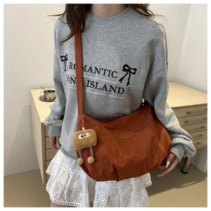 Detail of caramel nylon tote bag with fashion logo and plush cookie character charm