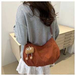 Burnt orange nylon tote bag detail with adjustable strap and fashion label charm