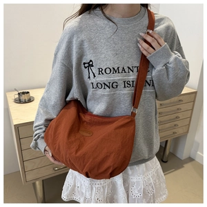 Caramel nylon crossbody tote bag shown on model in a cozy indoor setting