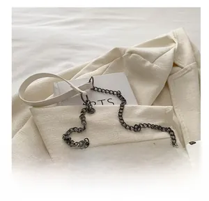 Detail of white quilted leather crossbody bag with metal chain strap and rivet trim