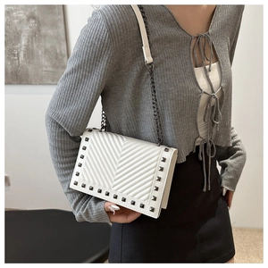 Detailed side view of white V-quilted shoulder bag with metal studs and chain strap