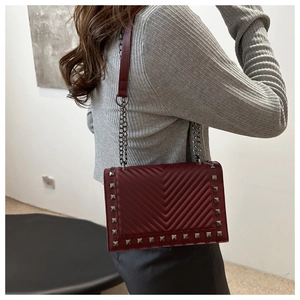 Detail of burgundy chevron quilted bag with silver stud trim and chain strap