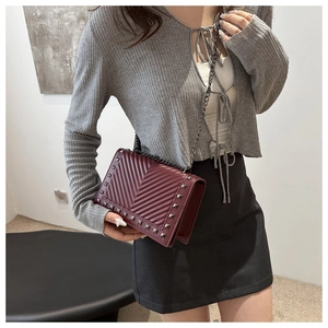 Deep red quilted leather crossbody bag with silver stud details and metal chain strap