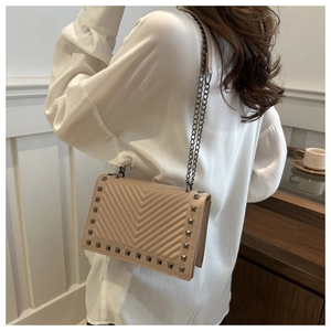 Detail of beige chevron quilted bag with square metal studs and chain strap