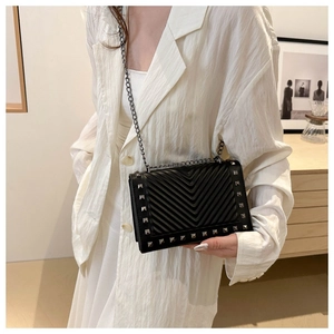 Detailed view of black quilted crossbody bag with silver studs and chain strap