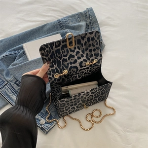 Umhängetasche mit Leopardenmuster, Goldkette und Überschlag vor Denim-Hintergrund