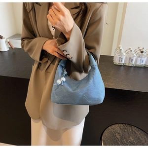 Détail du sac polochon en jean bleu avec surpiqûres losanges et breloque en perles