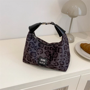 Sac hobo chic à motif léopard avec poignée en cuir noir sur une table blanche