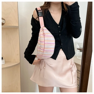 Detailed view of colorful striped crossbody chest bag worn with adjustable pink strap