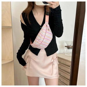 Close-up of a striped casual chest bag paired with a pink silk skirt and black cardigan