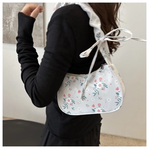 Detail of floral print shoulder bag featuring a decorative bow on the wide strap