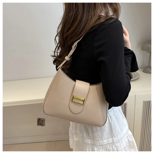 Chic beige leather baguette bag with gold buckle on shoulder of model in French style