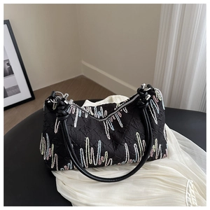 Detail of black quilted handbag featuring colorful embroidered stitching and leather handles