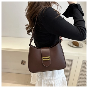 Close-up of a dark brown vintage hobo bag with gold buckle on a model in a minimal setting