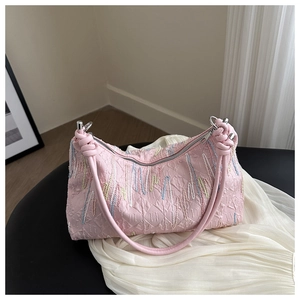 Macro detail of pink textured shoulder bag with colorful embroidery and knotted strap
