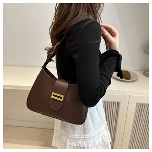 Detail of dark brown baguette bag with gold metal buckle and smooth faux leather