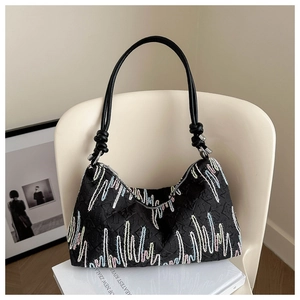 Detail of black shoulder bag featuring colorful embroidery and textured fabric