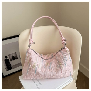 Detail of pink shoulder bag featuring colorful embroidery and silver spherical hardware