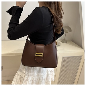 Classic dark brown shoulder bag with golden metal buckle in a minimalist interior setting