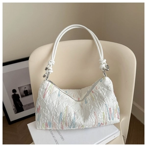 Detail of white quilted handbag with colorful vertical embroidery and rope shoulder strap