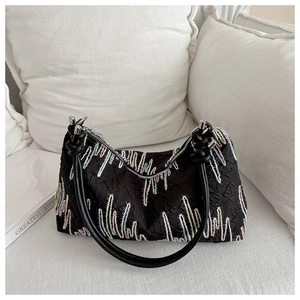 Close-up of black pleated tote bag with vibrant wavy embroidery and silver rings