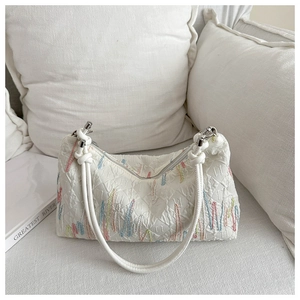 Macro detail of white textured tote with colorful embroidery and embossed IT logo