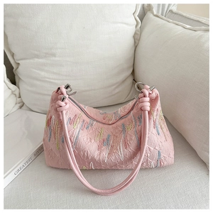 Detail of pink shoulder bag with colorful wave embroidery and woven handle design