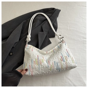 Detail of white quilted tote with colorful fluid lines and braided rope shoulder strap