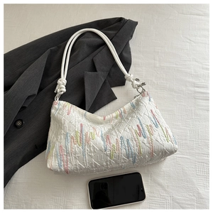 Detail of colorful wavy embroidery on white tote bag with twin cord handles and metal rings