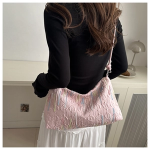 Close-up of pink quilted crossbody bag with colorful fringe embroidery on model