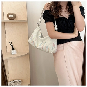 Detail of white tote bag with colorful embroidery and braided rope shoulder strap