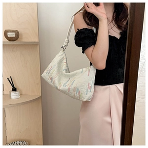 Detailed macro view of white pleated shoulder bag with colorful wavy embroidery patterns