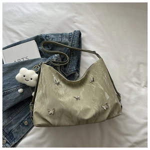 Detail of light green metallic tote with butterfly charms and plush cloud pendant