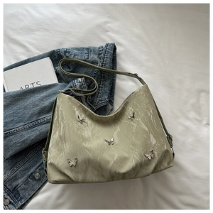 Detailed flat lay of green pleated shoulder bag with silver butterfly charms and strap