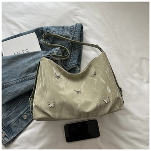 Detail of sage green wrinkled tote bag with silver butterfly studs and wide shoulder strap