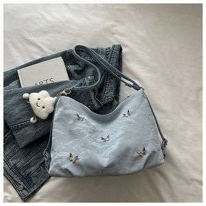 Detail of light blue hobo bag with pleated texture and silver butterfly accents
