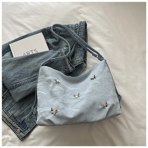 Close-up of light blue pleated cloud bag with silver butterfly charms and adjustable strap