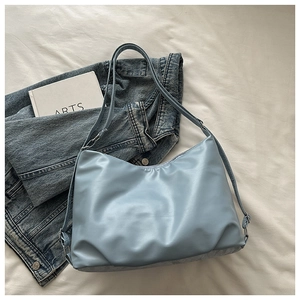 Top-down view of a light blue large capacity tote bag with soft pleats on white sheets