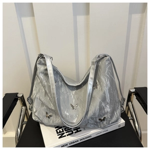 Detail of silver metallic backpack with laser pleated texture and metal butterfly accents