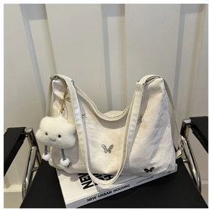 Detail of off-white tote bag with silver butterfly buckle and cloud plush charm