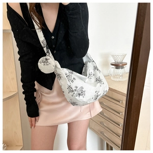 Floral corduroy hobo bag shown with a matching small round pouch on a model in a cozy room