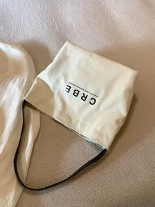 Close-up of minimalist straw canvas tote bag featuring contrast lettering and leather straps
