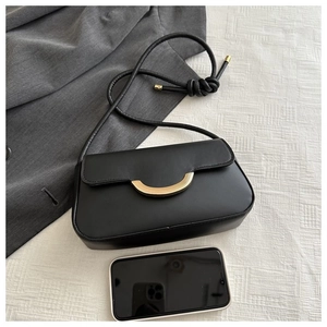Detailansicht der schwarzen Baguette-Tasche mit goldener Schnalle und Smartphone-Maßstab