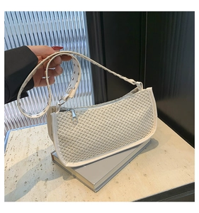 Detail of woven cream leather shoulder bag with silver rivet strap on marble background