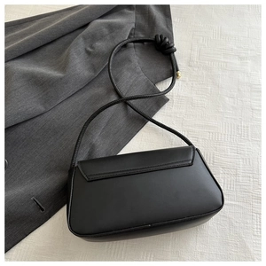 Detail der schwarzen Baguette-Tasche mit geknotetem Riemen und goldenen Beschlägen