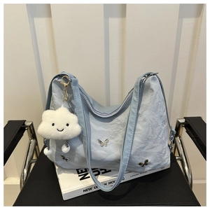 Detail of light blue pleated tote with silver butterfly charms and cloud pendant