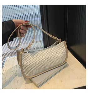 Detail of woven straw baguette bag with wide grommet strap and metallic zipper